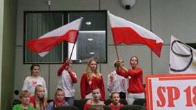 Kibice ze SP nr 18 dopingują swoich. Młodzież wymachuje dwoma flagami biało-czerwonymi
