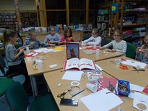 Dzieci siedzą przy stole i wykonują prace plastyczną