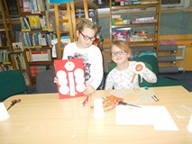 Dwie dziewczynki pozują do zdjęć ze swoimi pracami