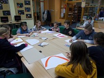 Dzieci siedzą przy stole i wykonują prace plastyczną