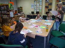 Dzieci siedzą przy stole i wykonują prace plastyczną