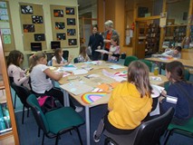 Dzieci siedzą przy stole i wykonują prace plastyczną