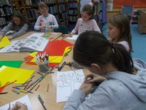 Dzieci siedzą przy stole i wykonują pracę plastyczną