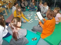 Dzieci słuchają opowiadania czytanego przez bibliotekarkę