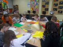 Dzieci wykonują pracę plastyczną, a bibliotekarka wspiera ich pracę