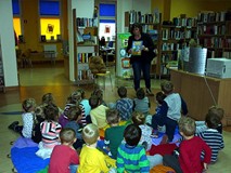 Bibliotekarka pokazuje dzieciom książeczki, których bohaterami są różne misie