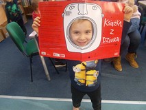 Chłopiec pozuje do zdjęcia z książką