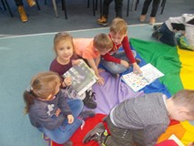 Dzieci siedzą na chuście i oglądają książki