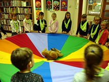 Zabawa z chustą integracyjną i misiem ZNAJDKIEM - dzieci usypiają misia