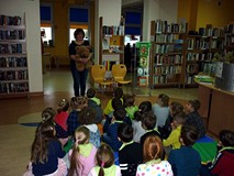 Dzieci siedzą na chuście integracyjnej i słuchają - opowiadanej przez bibliotekarkę - historii znale