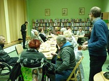 uczestnicy siedzą przy stołach i jedzą ciasto