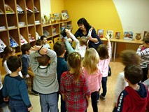 Dzieci stoją w grupie, prowadząca wyznacza osoby do kolejnej zabawy ruchowej