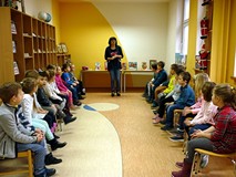 Dzieci zasiadły na krzesełkach w czytelni biblioteki, Pani Wiola wita je już świątecznie