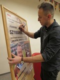 Marek Szymaniak składa pamiątkowy autograf podczas spotkania w Koszalińskiej Bibliotece Publicznej