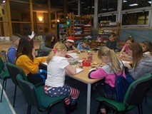 Dzieci siedzą przy stole i wykonują prace plastyczną