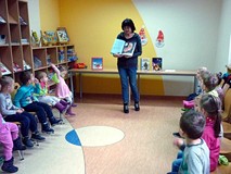 Bibliotekarka pokazuje dzieciom książeczki o Mikołajach