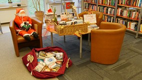 Wnętrze czytelni Koszalińskiej Biblioteki Publicznej. Dwa krzesła i stolik, na któreym jest kufer z 