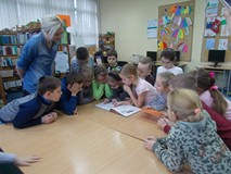 Dzieci szukają ukrytej informacji w książce pod nadzorem bibliotekarki