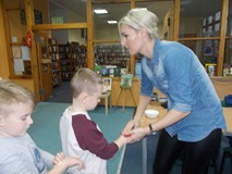 Bibliotekarka pomaga dzieciom w wykonaniu zmywalnych tatuaży