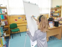 Dziewczynka rysuje na tablicy czapkę Mikołaja