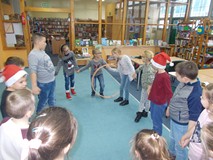 Dzieci stoją w kole i przekładają hula hop