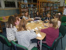 Dzieci siedzą przy atole i wykonują bałwany