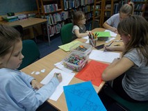 Dziewczynki siedza przy stole i wykonują pracę plastyczną