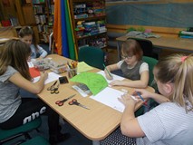 Dziewczynki siedza przy stole i wykonują pracę plastyczną