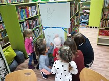Uczestnicy zajęć z zasłoniętymi oczami próbują narysować bałwanka
