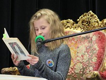 Uczestniczka powiatowego konkursu Wybieramy Mistrza Pieknego Czytania czyta wiersz siedząc na ozdobn