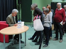 Jacek Fedorowicz podpisuje książki uczestnikom spotkania w Koszalińskiej Bibliotece Publicznej
