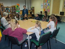 Dzieci siedzą przy stole i dyskutują z biblotekarką o sile reklamy