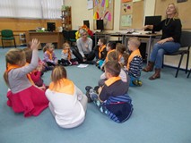 dzieci słuchają bibliotekarki siedząc na dywanie