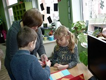 Bibliotekarka pomaga dzieciom w wykonaniu lapbooków