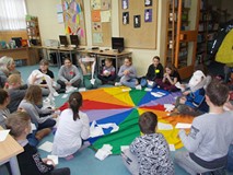 Dzieci siedza na chuście animacyjnej podczas wspólnej zabawy