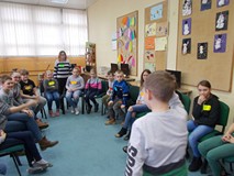 Dzieci siedzą w kole na krzesłach podczas wpólnej zabawy