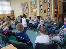 Dzieci siedzą w kole na krzesłach podczas wpólnej zabawy