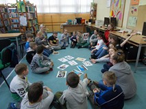 Dzieci siedzą na podłodze i słuchają opowieści bibliotekarki o twórczości Walta Disneya