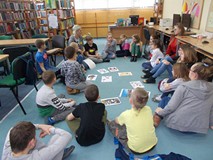 Dzieci siedzą na podłodze i słuchają opowieści bibliotekarki o twórczości Walta Disneya