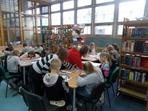 Dzieci siedza przy stolikach podczas wykonywania pracy plastycznej