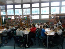 Dzieci siedza przy stolikach podczas wykonywania pracy plastycznej