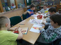 Dzieci siedza przy stolikach podczas wykonywania pracy plastycznej