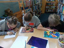 Dzieci siedza przy stolikach podczas wykonywania pracy plastycznej