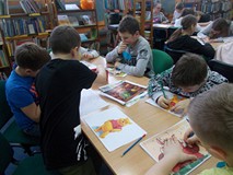 Dzieci siedza przy stolikach podczas wykonywania pracy plastycznej