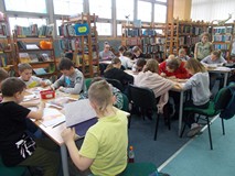 Dzieci siedza przy stolikach podczas wykonywania pracy plastycznej