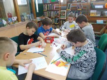 Dzieci siedza przy stolikach podczas wykonywania pracy plastycznej