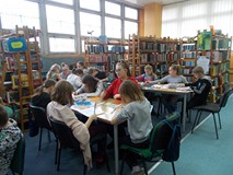 Dzieci siedza przy stolikach podczas wykonywania pracy plastycznej