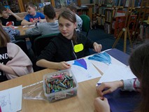 Dzieci siedza przy stolikach podczas wykonywania pracy plastycznej