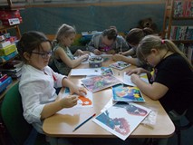 Dzieci siedza przy stolikach podczas wykonywania pracy plastycznej