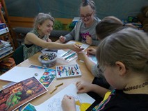 Dzieci siedza przy stolikach podczas wykonywania pracy plastycznej